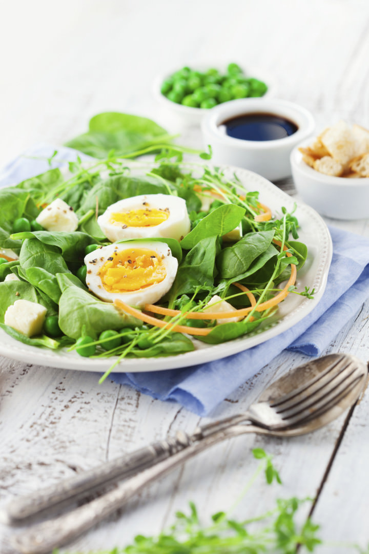 Fresh summer salad with green beans, spinach leaves and eggs on white wooden background, selective focus