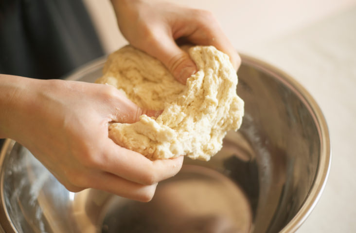 Woman making bagels, kneading dough, close up