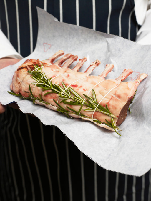 Butcher holding rack of lamb, mid section