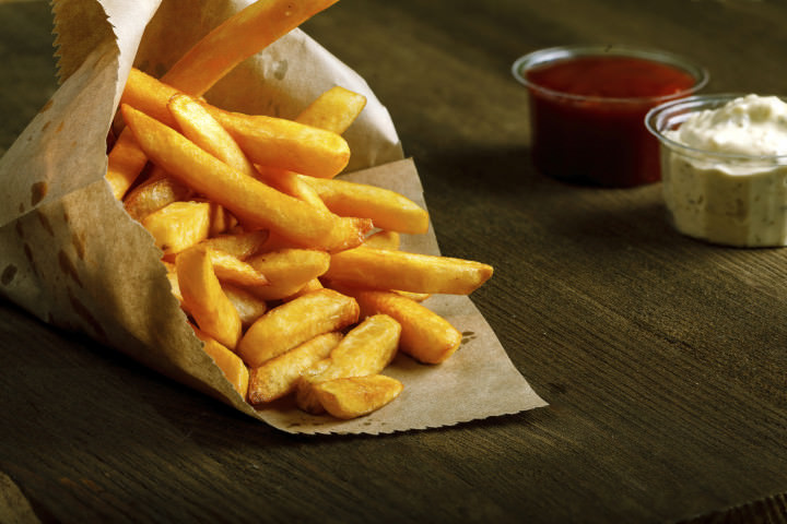 Fresh fried french fries with ketchup and white sauce on wooden background