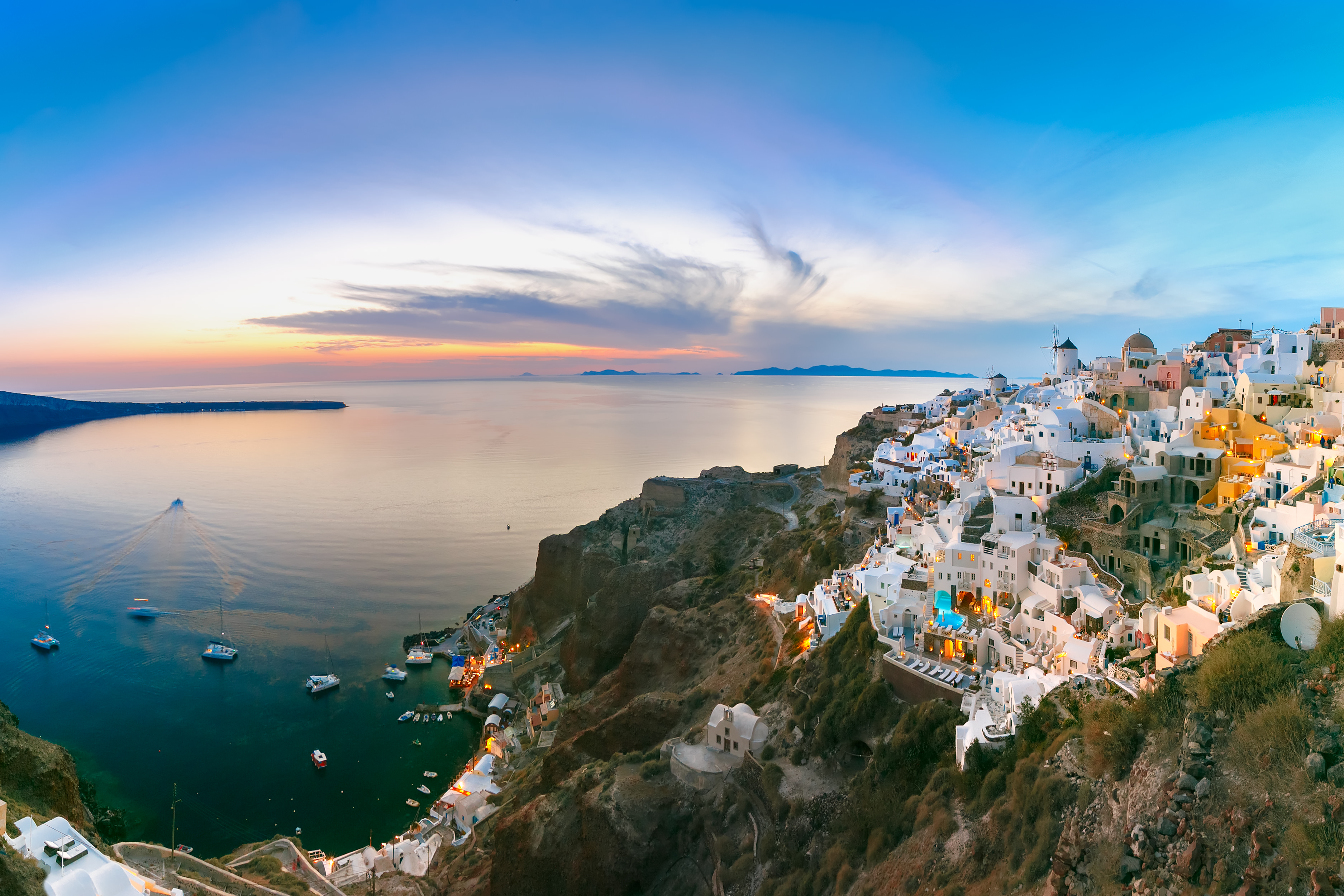Panoramic famous view, Old Town of Oia or Ia on the island Santorini, white houses and windmills at sunset, Greece
